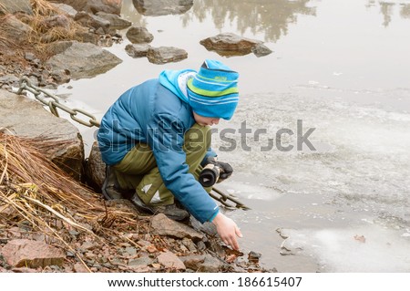 VIRBO, SWEDEN - MARCH 01, 2014: Young boy playing with ice on lake shore