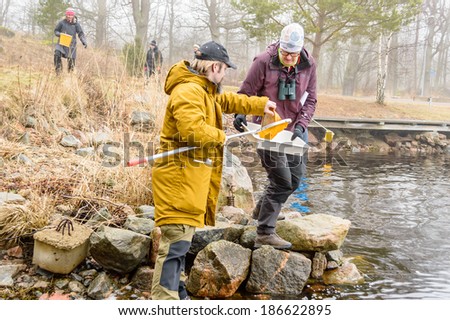 SMALAND, SWEDEN - MARCH 01, 2014: Water sampling with ring net. Team looking for water living animals to put in tray.