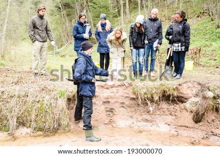 DALARNA, SWEDEN - MAY 06, 2014: Teacher educating group of pupils about silt and soil erosion in ravine landscape where erosion is eating away ground material in very fast rate.