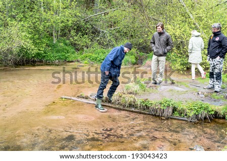 DALARNA, SWEDEN - MAY 06, 2014: Teacher educating about natural springs that bubble up from bottom of river. Rainy day.