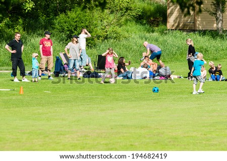 RONNEBY, SWEDEN - MAY 24, 2014: Group of people relaxing and having fun in public park. Green grass and ball play.