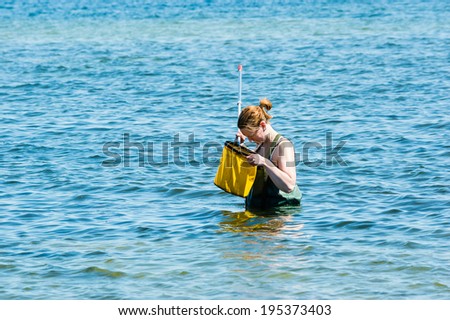 KALMAR, SWEDEN - MAY 26, 2014: Female in water with ring net examining the Baltic Sea for ecology education.