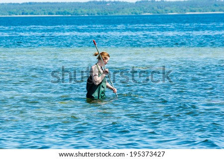 KALMAR, SWEDEN - MAY 26, 2014: Female in water with ring net examining the Baltic Sea for ecology education.