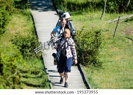OLAND, SWEDEN - MAY 26, 2014: Three bird watchers walking with telescopes and cameras.