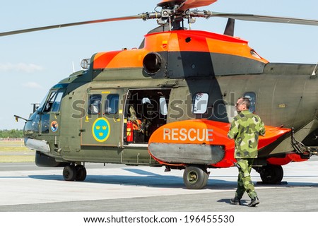 KALLINGE, SWEDEN - JUNE 01, 2014: Swedish Air Force air show 2014 at F 17 Wing. Search and rescue helicopter and soldier walking to it. Eurocopter AS332 Super Puma.