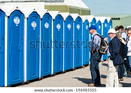KALLINGE, SWEDEN - JUNE 01, 2014: Swedish Air Force air show 2014 at F 17 Wing. People queue outside temporary toilets with blue doors.