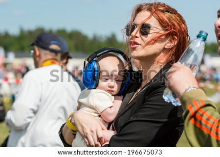 KALLINGE, SWEDEN - JUNE 01, 2014: Swedish Air Force air show 2014 at F 17 Wing. Small baby in ear protection in the arms of pretty woman.