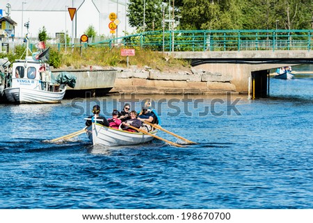 RONNEBY, SWEDEN - JUNE 14, 2014: Sillarodden, a local event with competing teams of fish mongers. Team of fishmongers rowing.