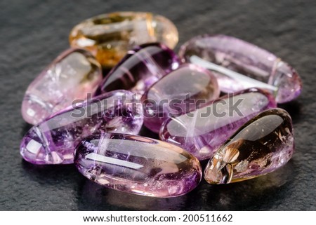 Set of purple and yellow ametrine beads on black stone plate.