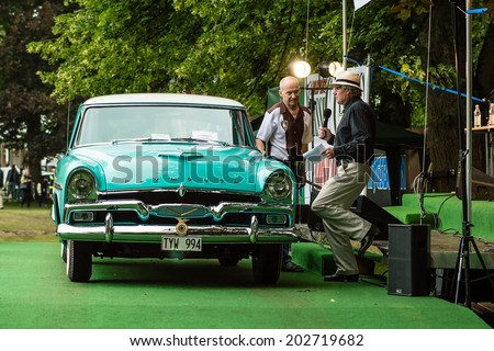 RONNEBY, SWEDEN - JUNE 28, 2014: Nostalgia Festival with classic cars and motorcycles as main attractions. Plymouth Ser 62 Cab 1956 owner being interviewed on stage.