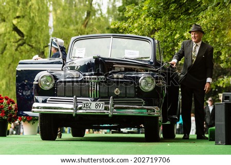 RONNEBY, SWEDEN - JUNE 28, 2014: Nostalgia Festival with classic cars and motorcycles as main attractions. Couple in contemporary dresses exit their black Mercury Cabriolet from 1946.