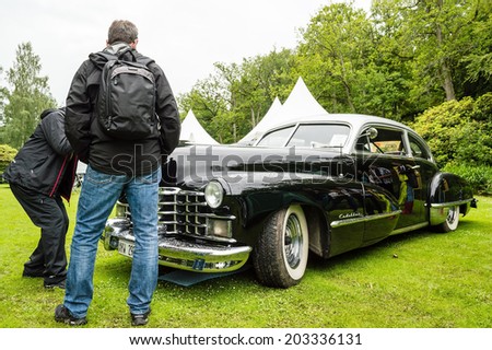 RONNEBY, SWEDEN - JUNE 28, 2014: Nostalgia Festival with classic cars and motorcycles as main attractions. Black Cadillac club coupe 1947. Visitors looking.