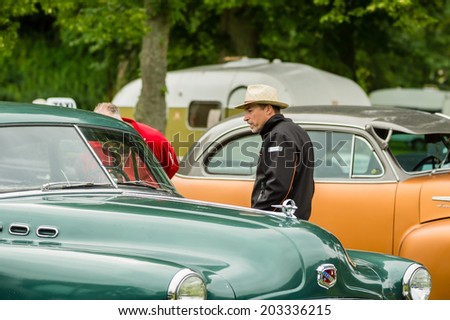 RONNEBY, SWEDEN - JUNE 28, 2014: Nostalgia Festival with classic cars and motorcycles as main attractions. Green Borgward inspected by visitor.