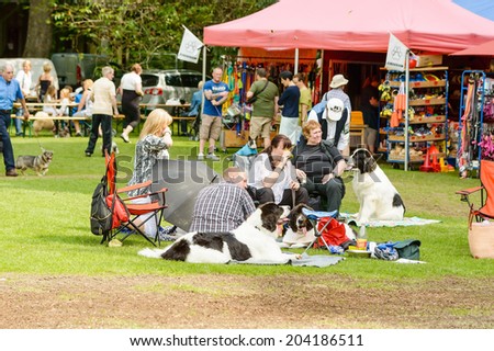 RONNEBY, SWEDEN - JULY 05, 2014: Blekinge Kennelklubb international dog show. People sitting with dogs on blankets on the ground.