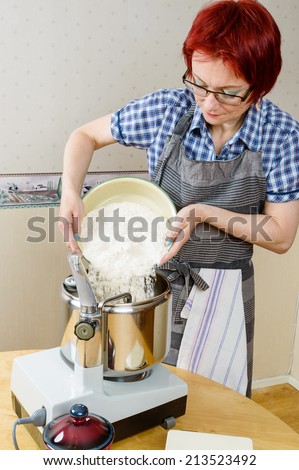Woman pour wheat flour into food processor while baking.