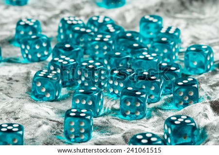 Lots of transparent blue dices spread out over grey cloth.