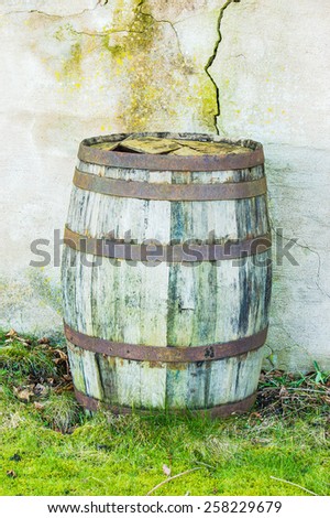 Old and weathered wooden barrel against concrete wall with cracks.