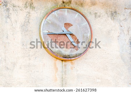 Old broken clock on industrial wall. Cover is broken and time has stopped. Place for text beside clock.