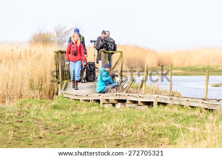 BEJERSHAMN, SWEDEN - APRIL 25, 2015: Photographer and ornithologists on bridge looking on birds in wetland as they arrive in spring. Bejershamn is a protected wildlife reserve known for birdlife.