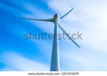 Wind turbine with fine blue sky and white clouds in background. Slight movement visible on blades.
