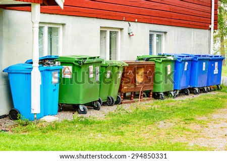 FROSO, SWEDEN - JUNE 29, 2015: Lot of garbage bins on the backside of a restaurant. Wooden cabinet in center.