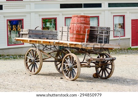 Old wooden wagon loaded with barrels and trunks. Here seen outside an old store building.