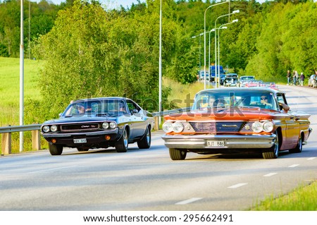 RONNEBY, SWEDEN - JUNE 26, 2015: Veteran car street cruise on public roads. Dodge challenger 1970 black passed by red Pontiac bonneville 1960.