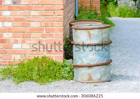 Two metal oil barrels standing in the corner of an old brick industrial building or factory.