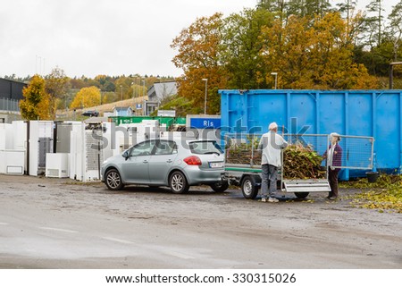 BUBBETORP, SWEDEN - OCTOBER 21, 2015: Unknown senior couple unloads a trailer full of garden waste on the recycle dump. Sorted garden waste will often end up as compost after a year or two.