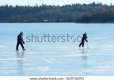 LISTERBY, SWEDEN - JANUARY 17, 2016: Two unknown young kids practice ice hockey on sea ice in the archipelago of Blekinge.