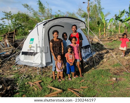 KBANGBANG, CEBU, PHILIPPINES - DECEMBER 5th 2013: A family in front of their emergency shelter tent after being made homeless by typhoon Haiyan,  Their destoyed house is in the background.