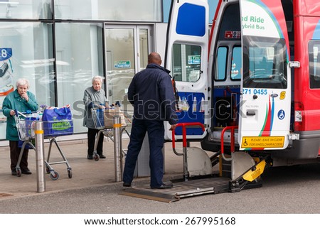 Coventry,UK - March 27th 2015: A hybrid park and ride minibus adpated to transport elderly or disabled shoppers waits for two seniors to board using the lift outside a supermarket.