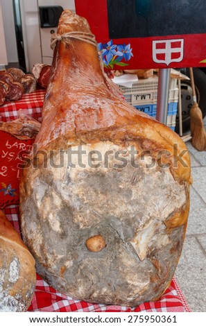 Traditional whole cured ham hanging on a market stall