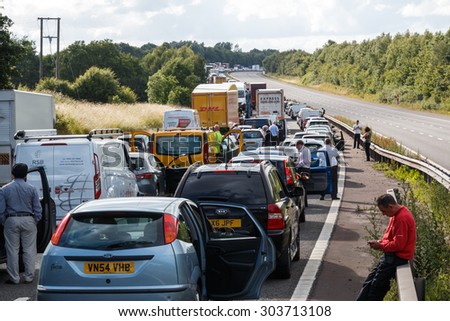 Warwickshire,UK - June 28th 2015:Drivers standing next to lines of queing traffic in a motorway traffic jam after an accident.  This happened on the M40 in England.