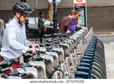 London,UK - August 7th 2015:A male cyclist rents a Santander rental bike in London.These can be rented at a series of places  around the city and are often called Boris bikes after the Mayor of London
