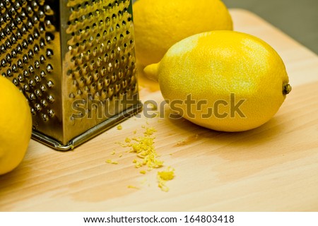 Lemons and lemon peel on wooden board with grater