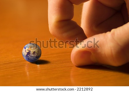 Small earth is going to be struck by somebody's finger - like it's a toy