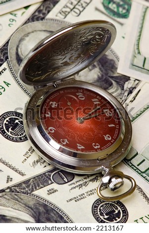 An old pocket watch on a 100 dollar bills