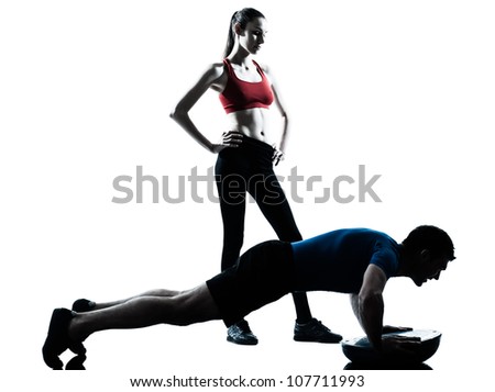 personal trainer man coach and woman exercising abdominals push ups on bosu silhouette studio isolated on white background - stock photo