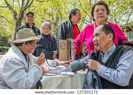 SHANGHAI, CHINA - APR 7, 2013: chinese doctor ausculting people  in fuxing park at the city of Shanghai in China on april 7th, 2013