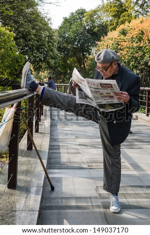 Shanghai - April 7: One Old Man Exercising Stretching Splits And Reading Newspaper In Gucheng Park On April 7th, 2013 In Shanghai