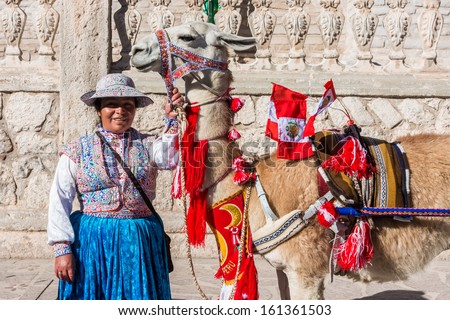 CHIVAY, PERU - JULY 29: Llama with peruvian flags and woman the peruvian Andes at Arequipa Peru on july 29th, 2013. The llama is a domesticated South American camelid, widely used by Andean cultures.
