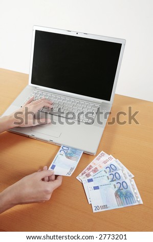 women puting euro bills inside the the cd-rom opening of a laptop computer