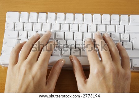 hand typing on a wireless white keyboard computer posed on atable
