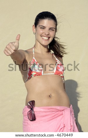 beautiful smiling bikini dressed young brazilian  woman saying hello in bazilian way  on the sand dune of  jericoacoara ceara state near fortaleza