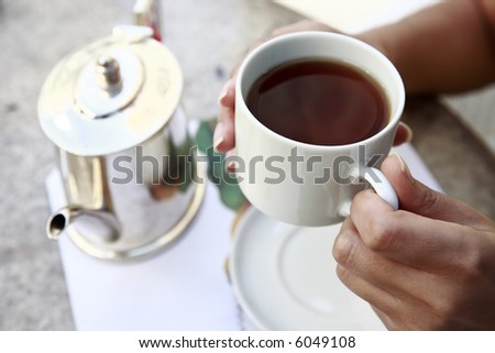 close up of hands serving tea in a cup from a teacup