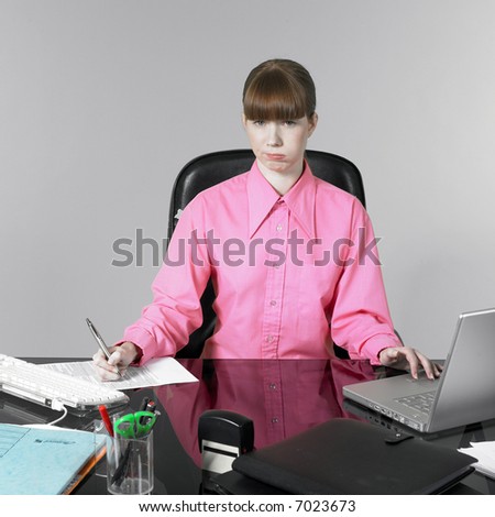 studio shot of a expressive and funny red hair young woman at the office desk having a hard time