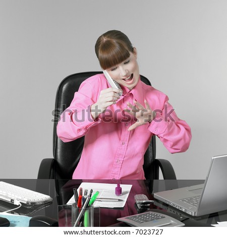 studio shot of a expressive and funny red hair young woman at the office desk having a hard time painting her fingernails