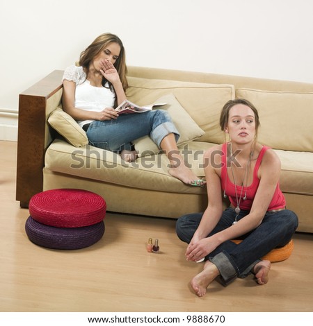 pictures in a living room of two young girls sitting on a couch getting bored
