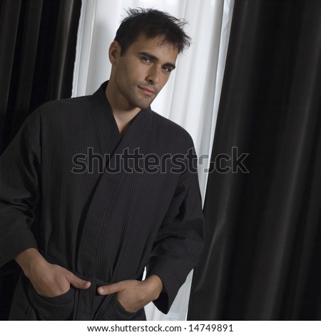portrait of handsome man in a brown bathrobe in front of a window